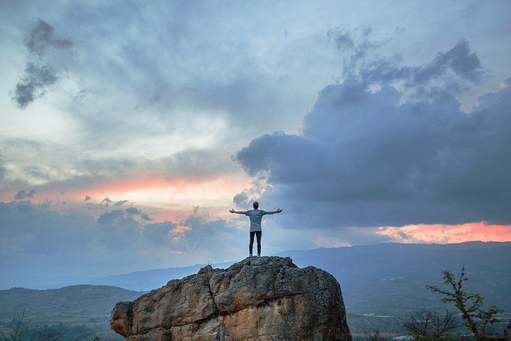 Men on top of the rock with the perfect cloudy day